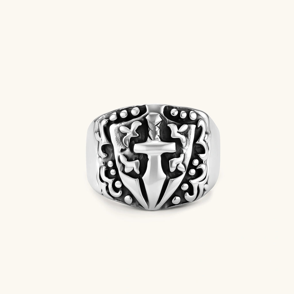 Silver 316L stainless steel men's signet ring with raised knight shield, cross motif, and ornate blackened scrollwork detailing.