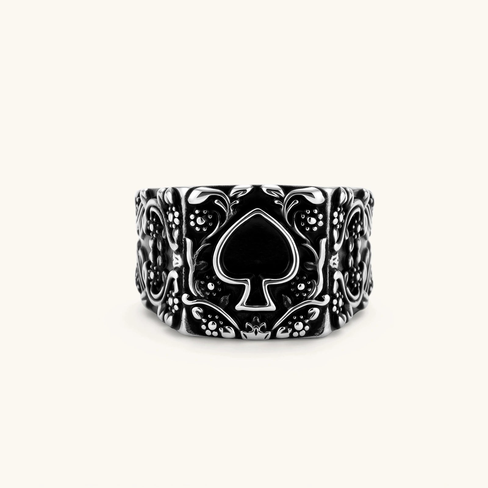 Silver-tone 316L stainless steel signet ring with black enamel spade motif and intricate floral scrollwork relief detail.