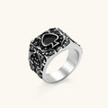 Silver-tone 316L stainless steel signet ring with black enamel spade motif and intricate floral scrollwork relief detail.