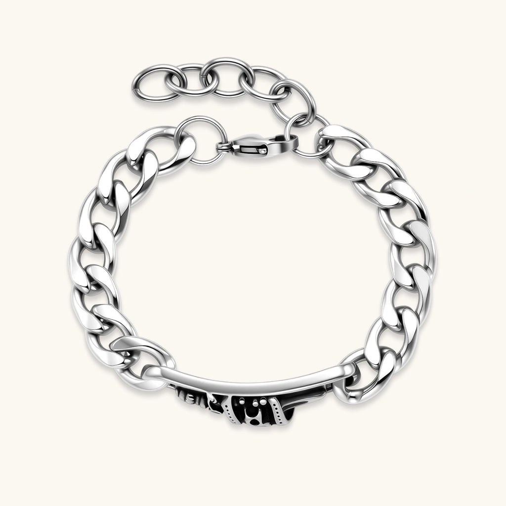 Silver 316L stainless steel Cuban chain bracelet with blackened skull and crown ID bar centerpiece, lobster clasp closure.