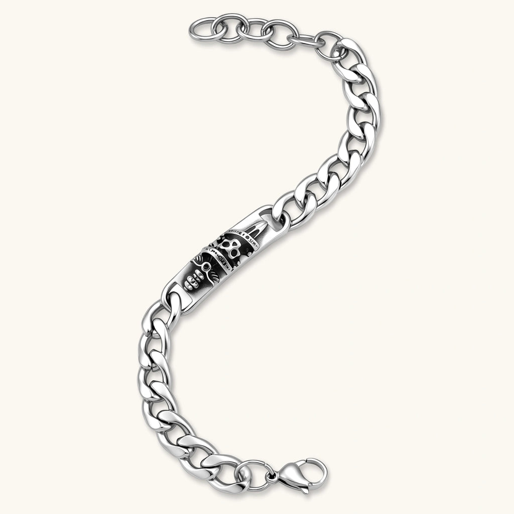 Silver 316L stainless steel Cuban chain bracelet with blackened skull and crown ID bar centerpiece, lobster clasp closure.