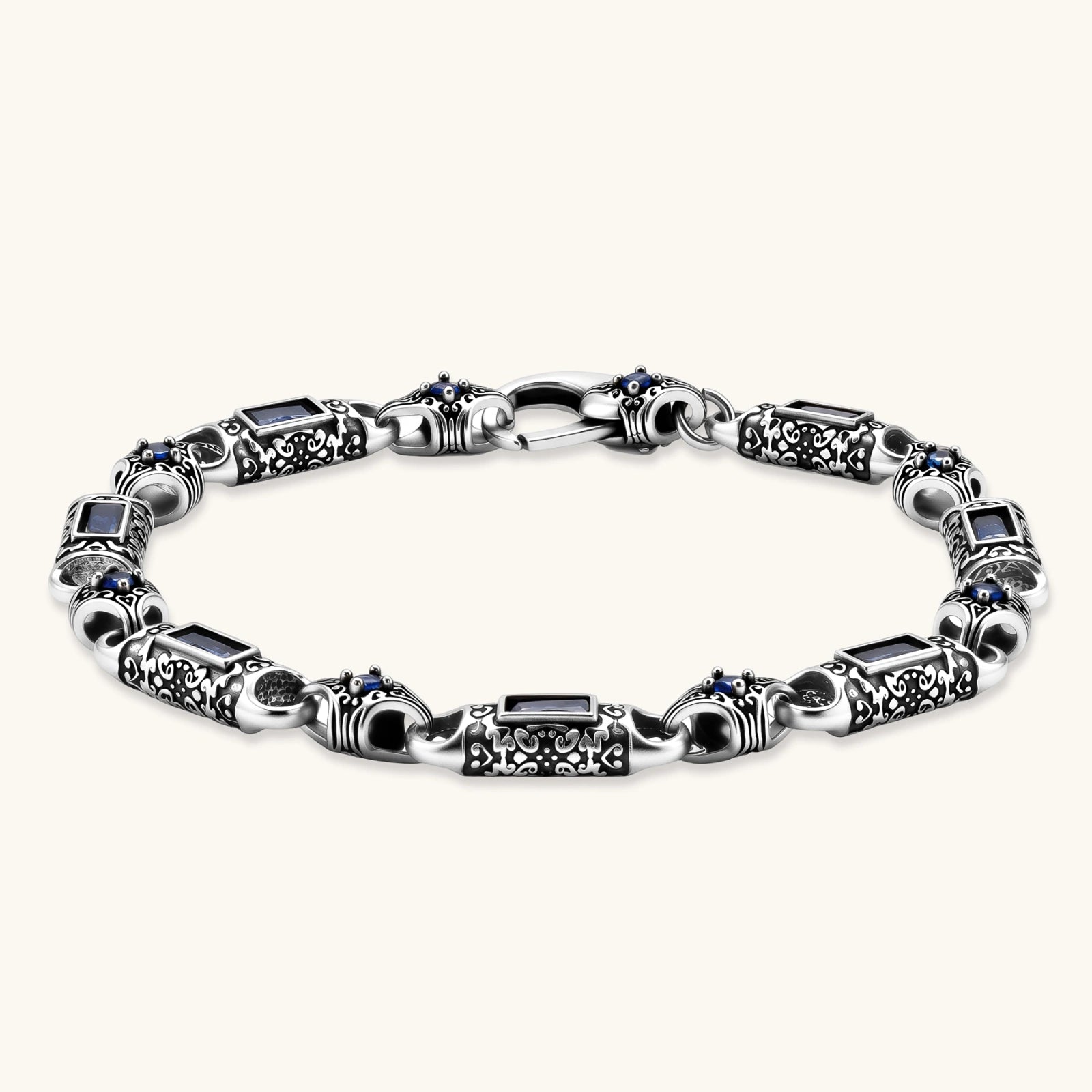 Oxidized silver stainless steel link bracelet with baguette blue CZ stones and intricate scroll engravings, lobster clasp.