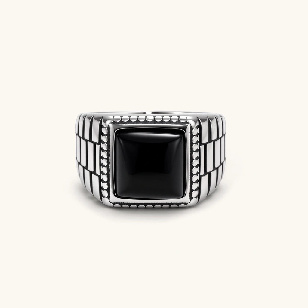 Silver stainless steel signet ring with checkered band texture, beaded border, and square black onyx cabochon stone center.